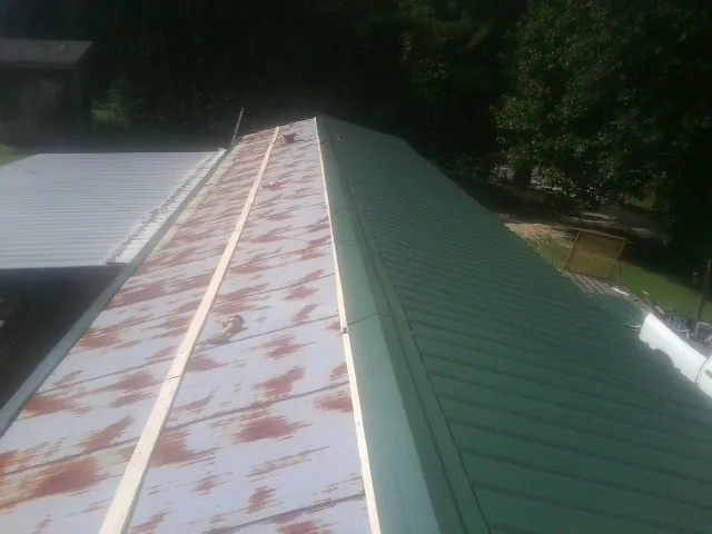 Old rusted panels beside newly installed green metal roofing — Wind Damage Roof Repair by Roofing Brothers in Virginia City