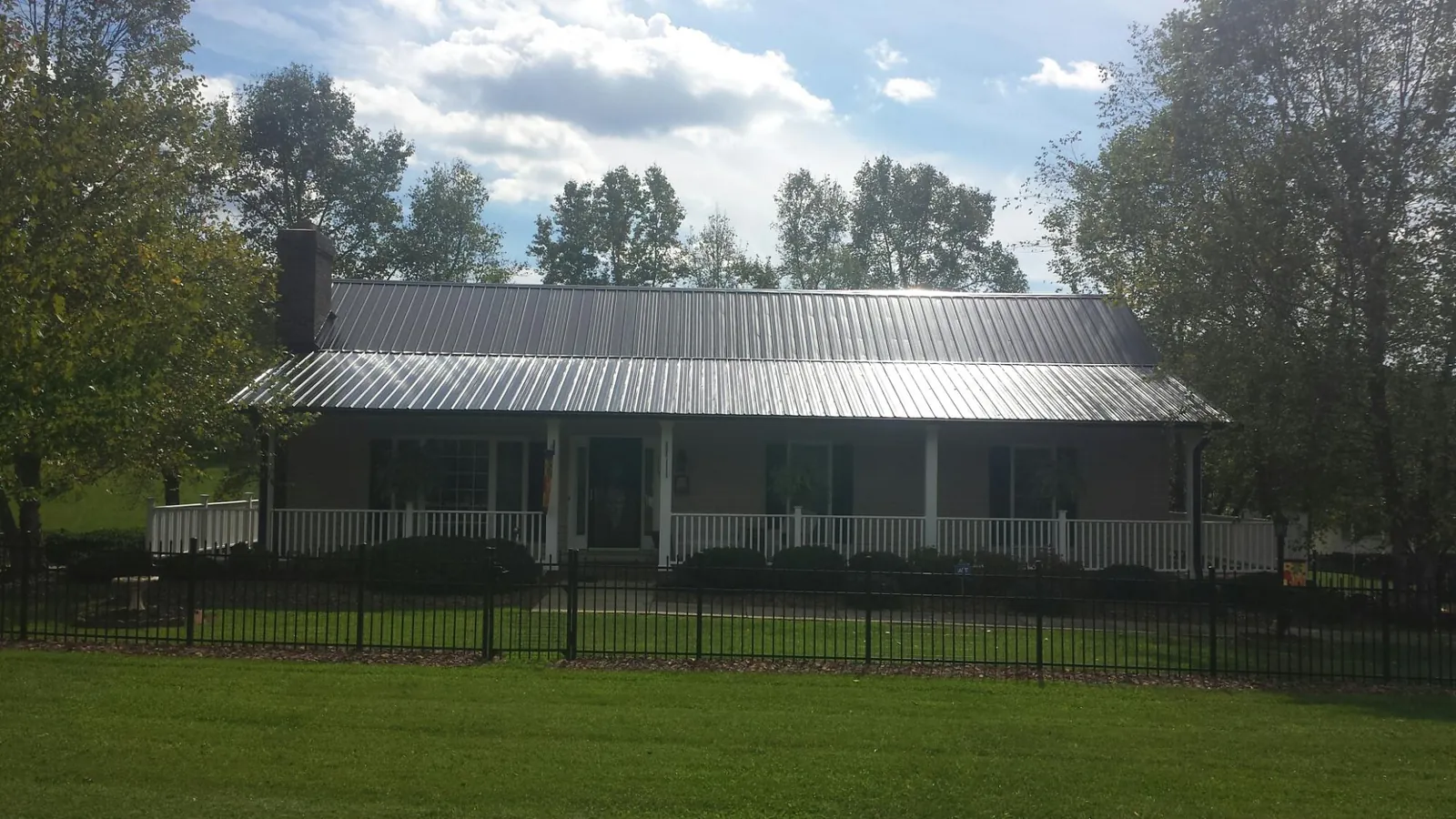 Gray metal roof on a brick ranch with a full width front porch — Gutter Guard Installation work by our crew in Virginia City