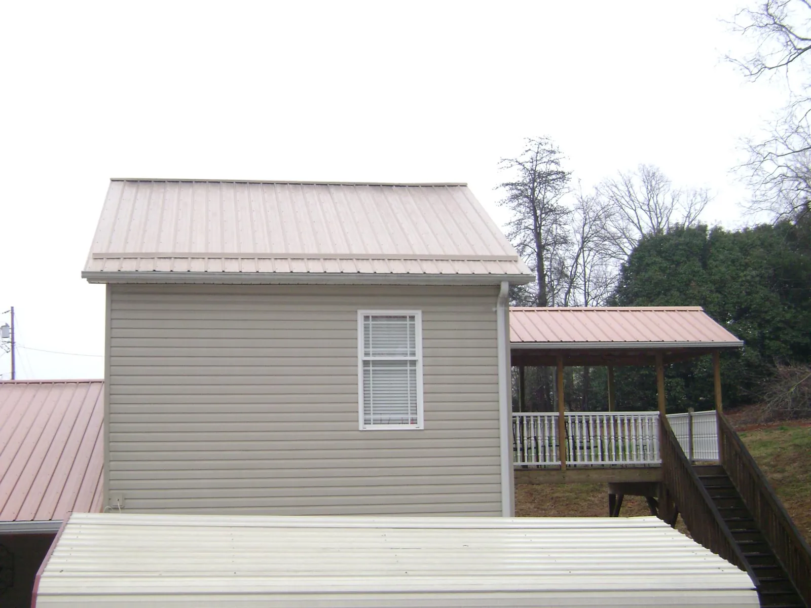 Tan metal roofs on a two story addition and attached porch, from a Roof Replacement job in Virginia City